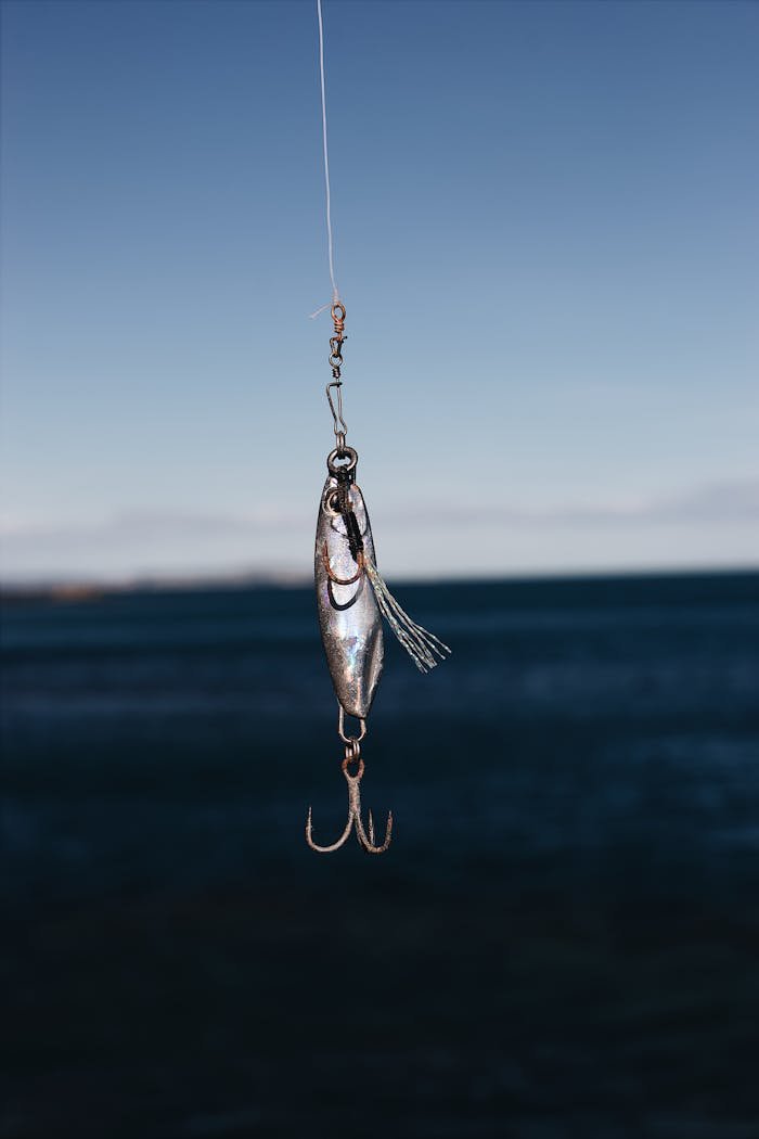 Services Close-up of a fishing lure hanging against a clear blue sea backdrop, ideal for outdoor and fishing themes.